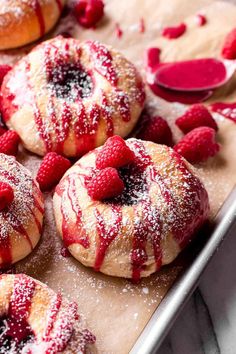 raspberry donuts on a baking sheet with powdered sugar