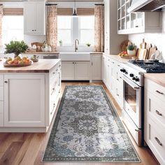 a kitchen with white cabinets and an area rug on the floor in front of the stove