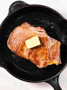 a piece of meat in a skillet with butter on it and some sort of cheese