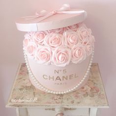 a pink hat box with roses and pearls on top