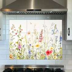 a kitchen stove top oven sitting next to a tiled backsplash with wildflowers on it