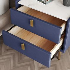 two blue drawers on a white table with a book and vase sitting on top of it