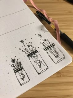 an open notebook with three mason jars filled with wildflowers on it next to a marker pen