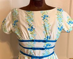 "This is a very pretty vintage dress from the late 1950's or very early 1960's. It is a petite size, and is a 22 inch waist. It is a very nice cotton fabric (almost a cotton sateen) with alternating stripes of pain cream and white with blue flowers and green leaves.  The waist has 3 bands of dark blue finished with bows. The waist is gathered in pleats. It has a metal and cloth zipper. The dress has a Jonathan Logan Label.  Condition is good- with only a tiny pen mark on the skirt, not really no Fitted Cotton Vintage Dress For Garden Party, Retro Cotton Vintage Dress With Vintage Pattern, 1950s Style Lined Cotton Vintage Dress, Vintage Cotton Dress For Garden Party, Cotton Vintage Dress For Garden Party, 1950s Cotton Vintage Dress, 1950s Cotton Vintage Dress For Vintage Fashion Events, 1950s Style Cotton Vintage Dress, Fitted Cotton Vintage Dress