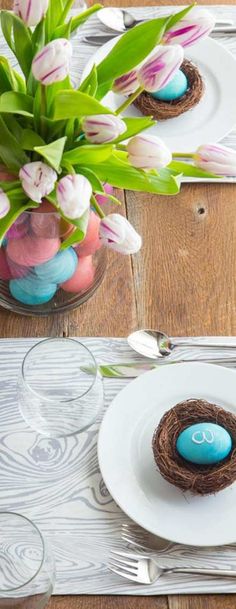 two plates with decorated eggs on them and flowers in vases next to each other