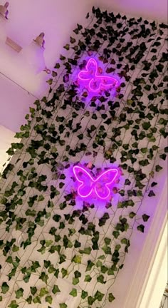 two neon butterflies on a wall with ivy