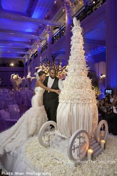 two people standing next to each other in front of a cake