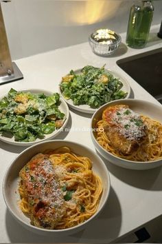 four bowls of pasta and greens on a counter