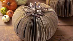 an open book with a bow on it sitting on a table next to pumpkins and gourds