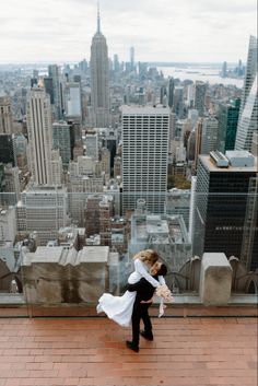 a bride and groom standing on top of a building in new york city, ny