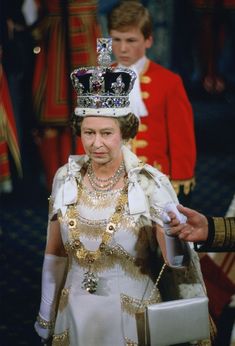 the queen of england is wearing a tiara and holding a white box in her hand