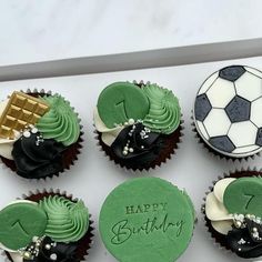 cupcakes decorated with green frosting and soccer themed icing are arranged in a box