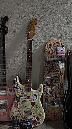 two guitars are sitting next to each other with stickers all over them on the wall