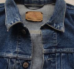 a denim jacket with a wooden tag on it