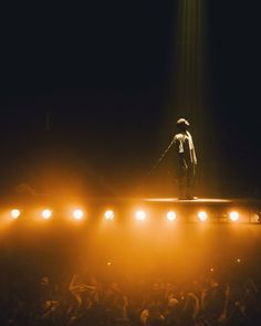 a man standing on top of a stage in front of a crowd at a concert