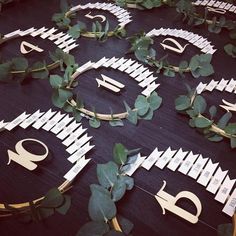 paper cut out faces are arranged on a table with greenery and leaves around them