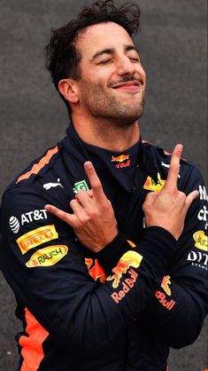 a man with his hands in the air while standing next to a race car driver