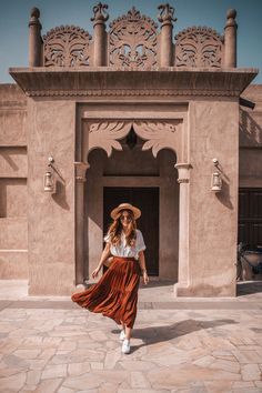 a woman in a hat and dress is walking by a building