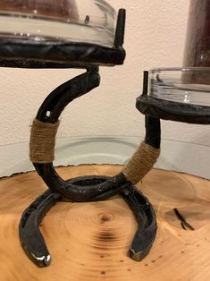 a wooden table topped with two glass dishes and a black iron ring on top of it