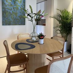 a wooden table with chairs around it and a vase filled with flowers on the table