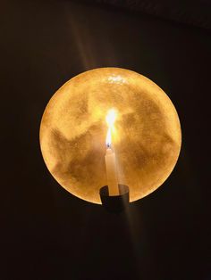 a lit candle in the middle of a dark room