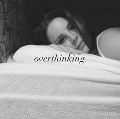 a black and white photo of a woman laying in bed with the caption overthiking