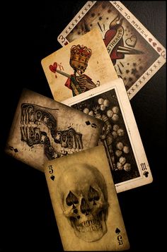 four playing cards with skulls on them and one has a skull in the middle,