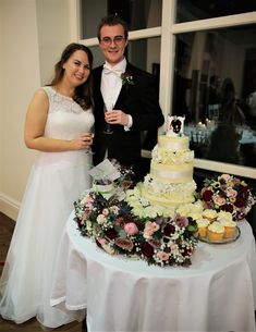 a man and woman standing next to a table with cupcakes