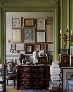 a room filled with lots of books and pictures on the wall above a chest of drawers