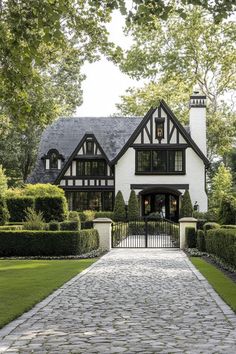 Modern Tudor house with lush garden and cobblestone path. The charming fusion of history and contemporary flair in modern Tudor houses can transform your living space from “just nice” to “royalty-approved.” Modern English Tudor, Modern Tudor House, Cobblestone Path, House Brick, Modern Tudor, Brick Cottage