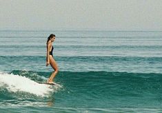 a woman riding a wave on top of a surfboard