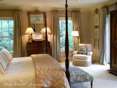 a bedroom with a four poster bed, chair and mirror on the wall next to two windows