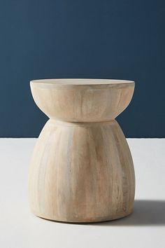 a wooden bowl sitting on top of a white table next to a blue wall in the background