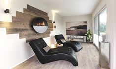 a living room with two black leather chairs and a round mirror on the wall above it