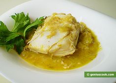 a white plate topped with fish covered in gravy and garnished with parsley