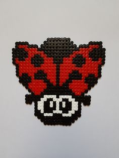 a red and black beaded brooch sitting on top of a white table