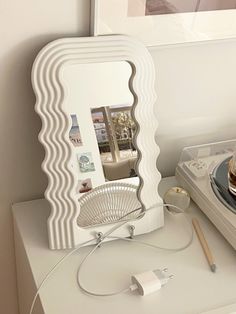 a white table with an electronic device on it and a mirror in the middle that is shaped like waves