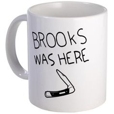 a white coffee mug with the words brooks was here on it and a knife sticking out of it