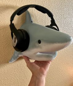 a person is holding up a shark headphone