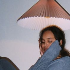 a woman is covering her face under a lamp