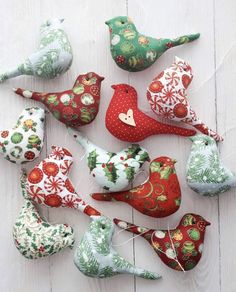 christmas ornaments are laid out on a white wooden surface, including red and green birds