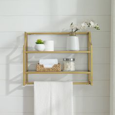 a bathroom shelf with towels, soaps and other items on it in front of a white wall