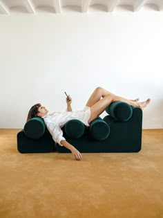 a woman laying on top of a green couch holding a cell phone in her hand