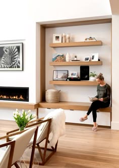 a woman sitting on a chair in front of a fire place with shelves above her