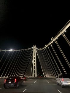 cars driving across a bridge at night with lights shining on the top and bottom part