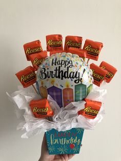 a hand holding a birthday cake with candy on it and the words happy birthday written on it