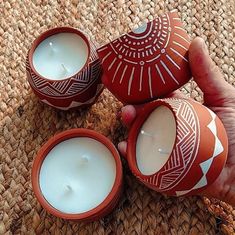 three red and white candles sitting next to each other on a woven tablecloth covered floor