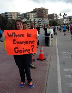 a woman holding a sign that says where is everyone going?