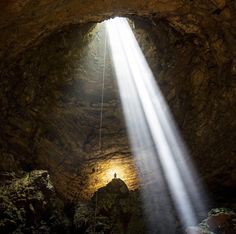 the light shines brightly through the cave's ceiling as it is suspended by a rope