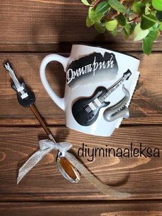 a coffee cup with an electric guitar on it next to a pair of sunglasses and a plant